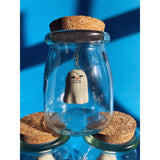 An uncomfortable ceramic ghost figurine suspended in a glass jar. 