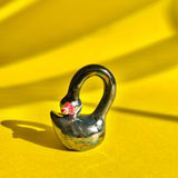 A black, ceramic swan figurine with an exaggeratedly long neck, resting its head on its own back, making a loop with its neck.