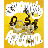 A cluster of ceramic swan figurines with hand lettering surrounding them saying "Swanning around."