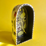 An arched ceramic wall shelf featuring an illustration of a stylized Atropa Belladonna plant. Front view