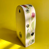 An arched ceramic wall shelf featuring an illustration of a stylized Atropa Belladonna plant. Side view